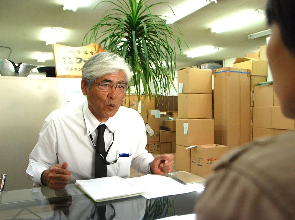 事務所の応接テーブルでインタビューに答える有限会社コーエー社 社長・上原康永